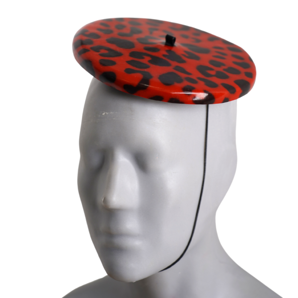 Latex Fashion by Vex A mannequin head displays the Print Mini Beret - Red Leopard, a round fascinator hat with black leopard spots and a thin black chin strap, set against a white background.